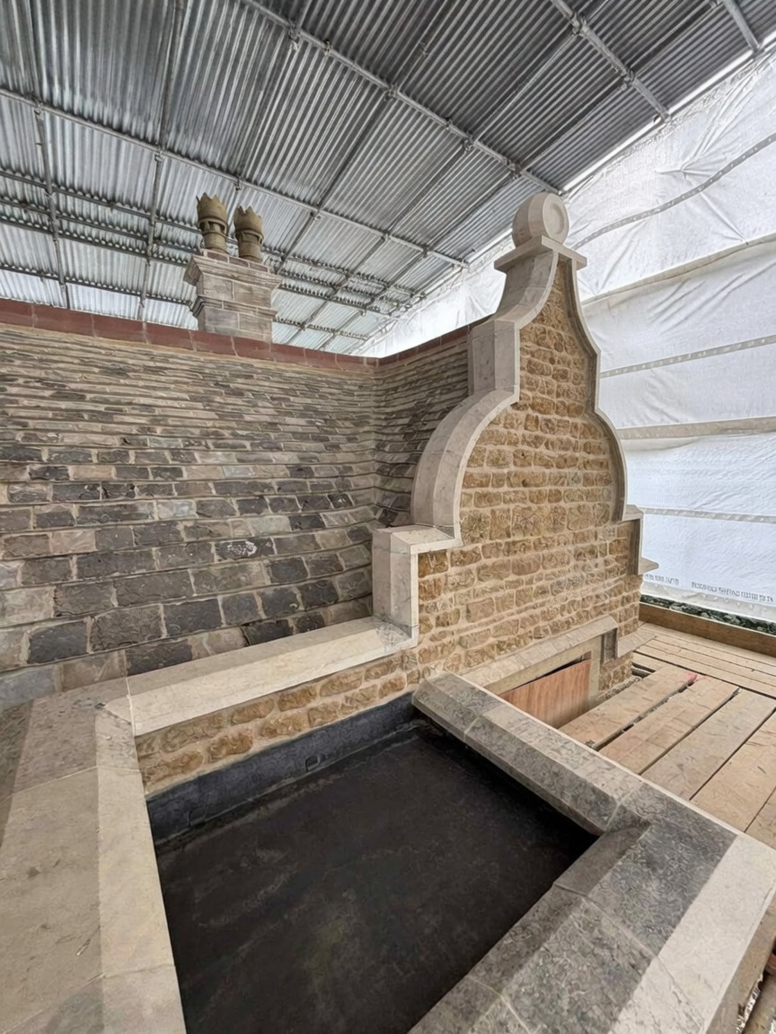 Rebuilt shaped stone gable with moulded limestone coping, kneelers and ball finial, sheltered under a temporary scaffold roof during conservation works