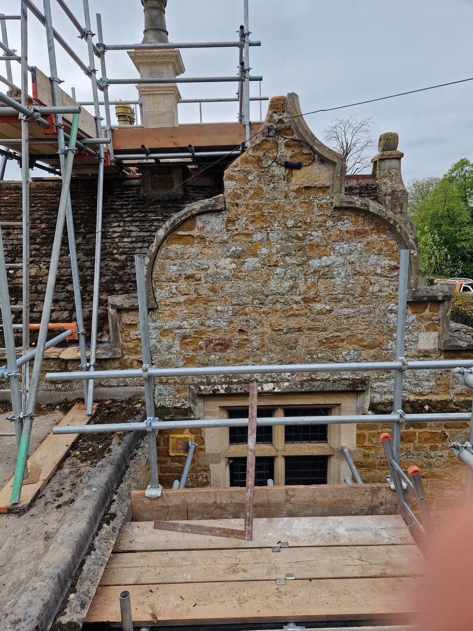 Shaped Dutch gable and stone mullion window under scaffolding during conservation repairs to a historic ironstone building